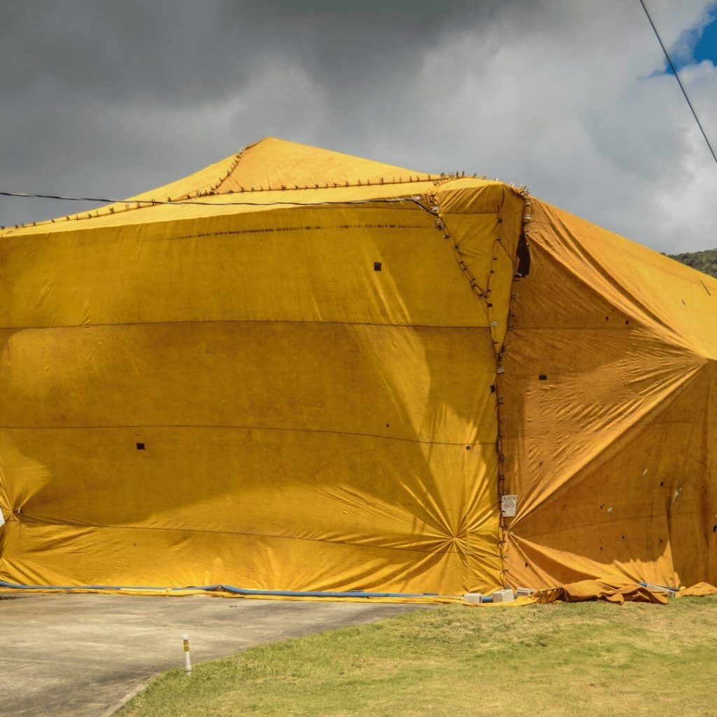 House covered by a yellow fumigation tent