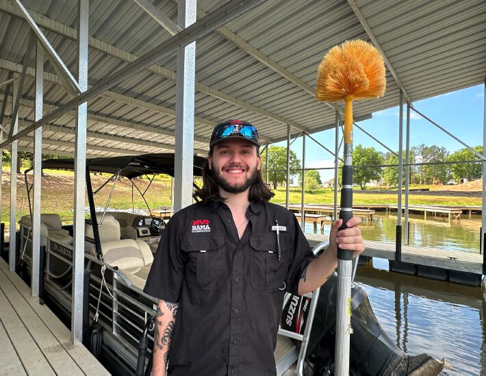 Bama technician clearing spider webs from a boat dock